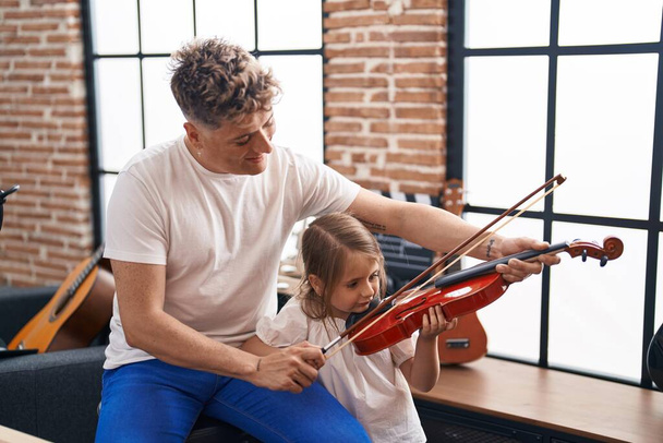 Father and daughter playing violin at music studio - Foto, imagen
