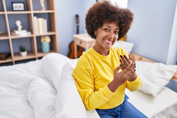 Afrikai amerikai nő mosolyog magabiztos ül az ágyon a hálószobában - Fotó, kép