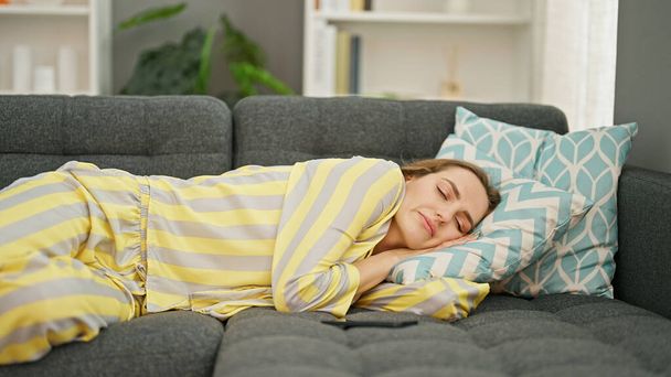 Young blonde woman lying on sofa sleeping at home - Photo, image