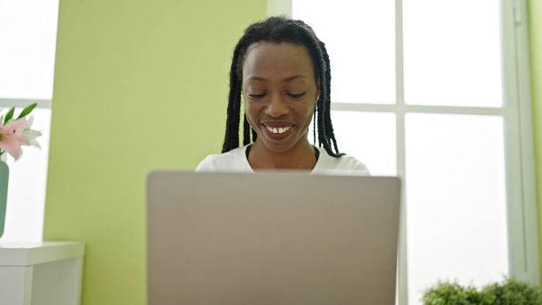 Mujer afroamericana usando portátil sentado en la mesa en casa - Foto, Imagen
