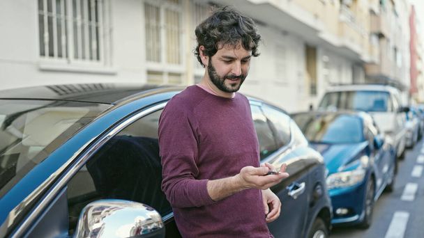 Young hispanic man smiling confident holding key of new car at street - Photo, image