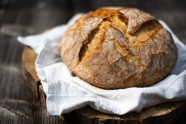 Geleneksel mayalanmış mayalı ekmek. Köy ahşap bir masada derisi pişmiş. Sağlıklı yemek fotoğrafçılığı - Fotoğraf, Görsel