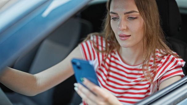 Junge blonde Frau fährt mit Smartphone Auto auf Straße - Foto, Bild
