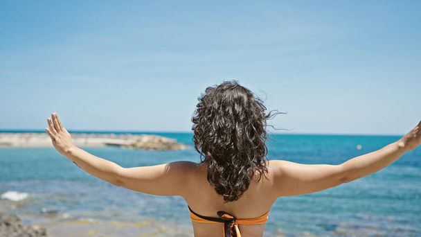 Νεαρή όμορφη Ισπανίδα τουρίστρια στέκεται ανάποδα τεντώνοντας τα χέρια στην παραλία - Φωτογραφία, εικόνα