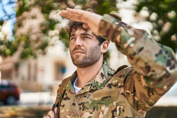 Młody żołnierz wojskowy salutuje w parku. - Zdjęcie, obraz
