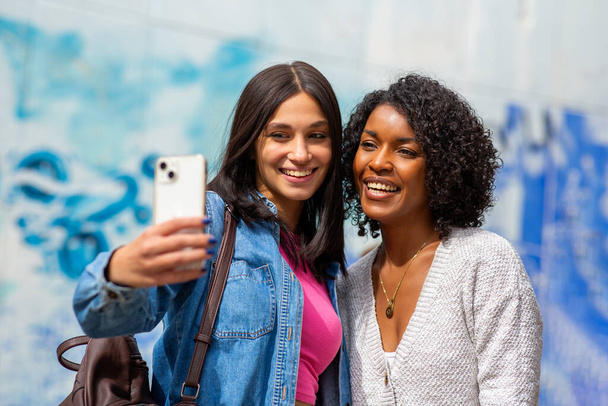 Portrait two female friends taking selfie with smart phone - Foto, afbeelding