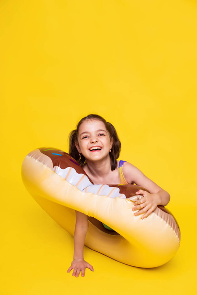 funny girl test for strength of inflatable ring on yellow background. happy summer holidays - Fotoğraf, Görsel