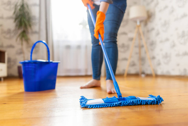 Imagen recortada de una mujer joven en ropa casual lavando un piso de madera con una fregona de microfibra húmeda, haciendo tareas, limpieza rutinaria, concepto de trabajo de limpieza - Foto, imagen