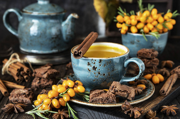 Concept of warm autumn beverage. Hot herbal tea with sea buckthorn and spices  - Foto, Bild