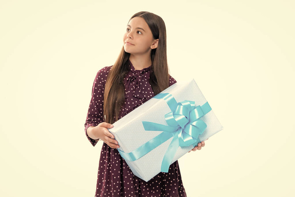 Portrait of happy smiling teenage child girl. Surprised teenage child holding gift box on white isolated background. Gift for kids birthday. Christmas or New Year present box - Fotó, kép