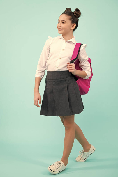 Schoolgirl in school uniform with school bag. Teenage girl student on blue isolated background. Learning knowledge and children education concept - Foto, Imagem