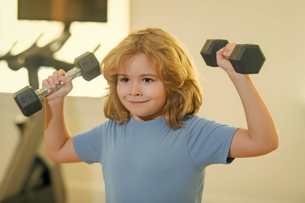 Child workout kid in gym. Sport activities at leisure with children. Boy holding dumbbells - Fotografie, Obrázek