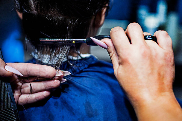 парикмахер режет затылок ножницами под расческой. Модные стрижки - Фото, изображение