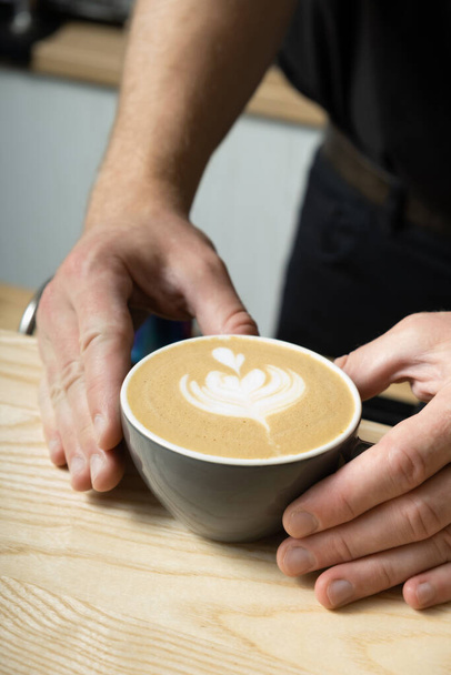 Barista hands serving coffee latte with art. - 写真・画像