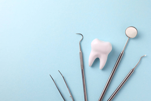 Dentistry concept. Model of a tooth and dental instruments on a colored background with space for text. . High quality photo - Fotó, kép