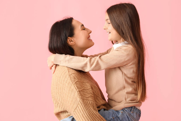 Little girl and her mother in knitted sweaters on pink background - Photo, Image