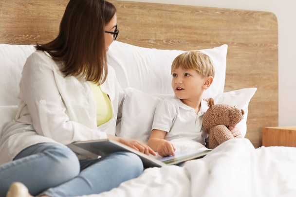 Nanny reading story to little boy in bedroom - Foto, Bild