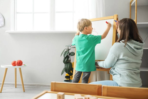 Маленький мальчик с няней рисует дома - Фото, изображение