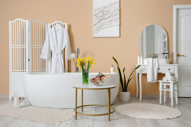 Interior del baño con bañera, tocador y flores narcisas - Foto, imagen