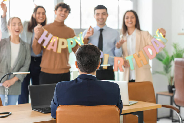 Young man with his colleagues at birthday party in office, back view - Фото, зображення