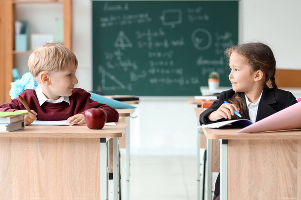 Однокласники зі шкільними конусами сидять за столами в класі - Фото, зображення