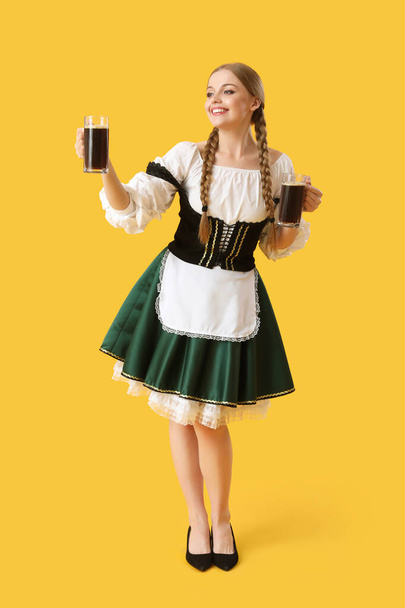 Beautiful Octoberfest waitress with beer on yellow background - Foto, afbeelding