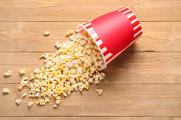 Bucket with tasty popcorn on wooden background - 写真・画像