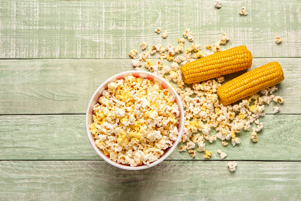 Bucket with tasty popcorn on green wooden background - Фото, изображение