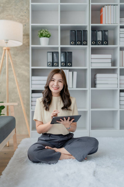 Happy young woman with tablet in living room on sofa. Young happy woman lie playing smart tablet at home. Beautiful young asian women using tablet computer - Photo, Image