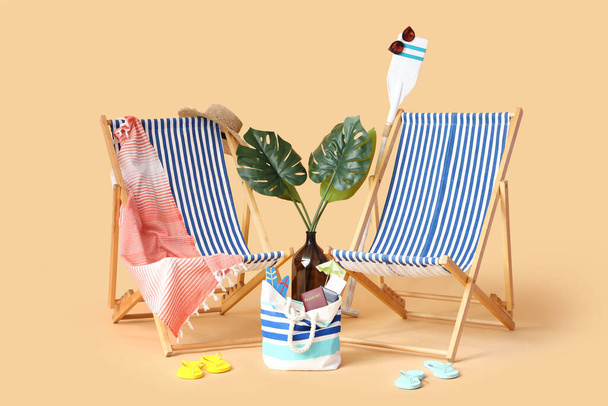 Deckchairs with palm leaves and beach accessories on beige background. Travel concept - 写真・画像