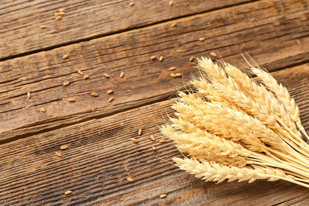 Bundle of wheat ears and grains on wooden table - Photo, Image