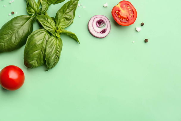 Taze fesleğen, kiraz domatesleri ve yeşil arka planda bir dilim kırmızı soğan. - Fotoğraf, Görsel