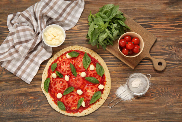 Tasty pizza and ingredients on wooden background - Photo, Image