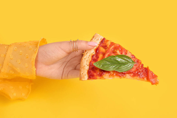 Woman holding slice of tasty pizza on yellow background - Photo, Image