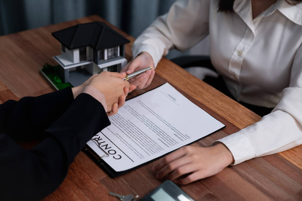 Completing the final step of the house loan process, the buyer signs the loan contract paper with a pen on the desk, securing the ownership of the property. Enthusiastic - Photo, Image