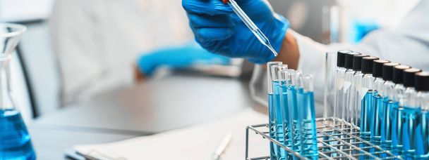 Skupina specializovaných vědců provádí chemický experiment v lékařské laboratoři, pečlivě ukládat přesné množství tekutiny z pipety do zkumavky pro vývoj vakcíny nebo antibiotik. Neoterický - Fotografie, Obrázek