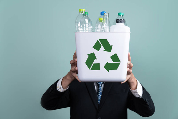 Podnikatel drží koš naplněný plastovou lahví na izolovaném pozadí. Odpovědnost podniků za ekologické prostředí a komunitu. Koncepce třídění a nakládání s odpady. Změnit - Fotografie, Obrázek