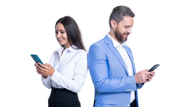 cheerful couple of businesspeople messaging in formalwear. photo of businesspeople messaging on phone. businesspeople messaging isolated on white background. businesspeople messaging in studio. - Φωτογραφία, εικόνα