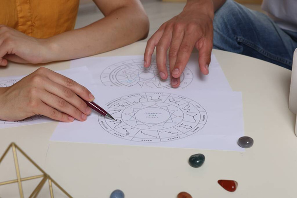 Astrologer showing natal charts to client at table, closeup - Fotó, kép