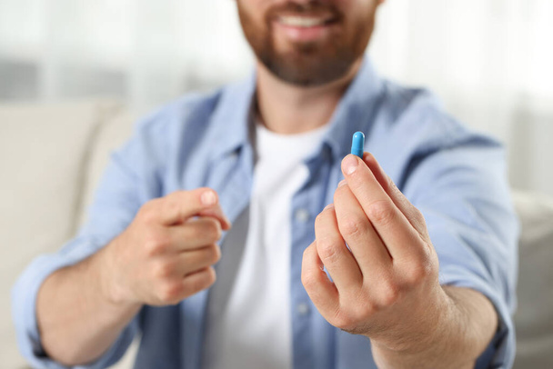 Man showing pill indoors, closeup. Space for text - Фото, изображение