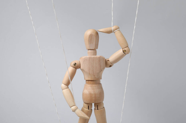 One wooden puppet with strings on light grey background - Foto, imagen