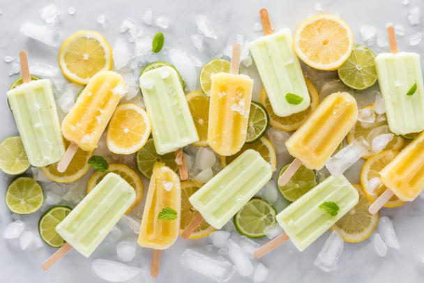 Glaces rafraîchissantes au citron et citron vert sur un lit de tranches de citron et citron vert avec de la glace.  - Photo, image