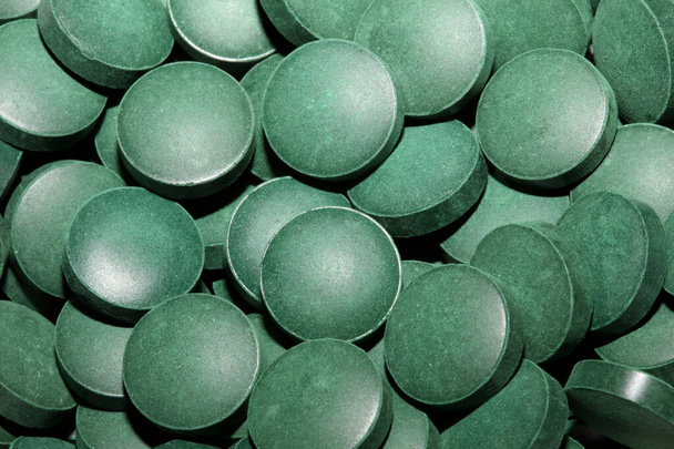 Πράσινα φύκια στρογγυλά χάπια κλείστε ιατρική Spirulina platensis διαστημική τροφή σύγχρονη υψηλής ποιότητας μεγάλο μέγεθος σούπερ τροφίμων στιγμιαίες εκτυπώσεις απόθεμα φωτογραφίας - Φωτογραφία, εικόνα