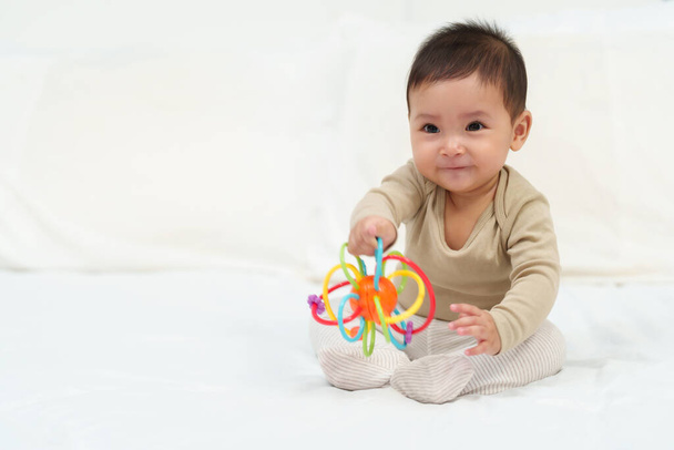 infant baby playing with colorful rubber bites toy on a bed - Foto, Imagem