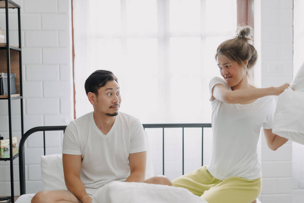 Asian wife and husband playing pillow fight funny and laugh on the bed. - Foto, imagen