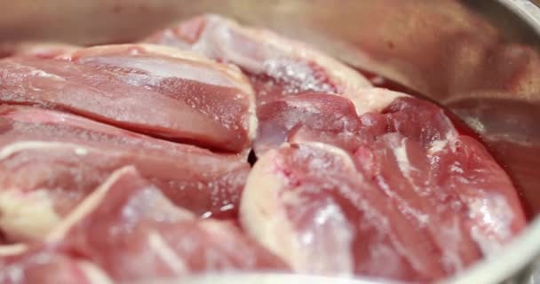 Cijfers van rauw, vers vlees in een kom close-up in de keuken voor het koken. - Video