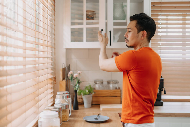Asian man preparing his easy breakfast in the kitchen in warm light morning. - Foto, Imagem
