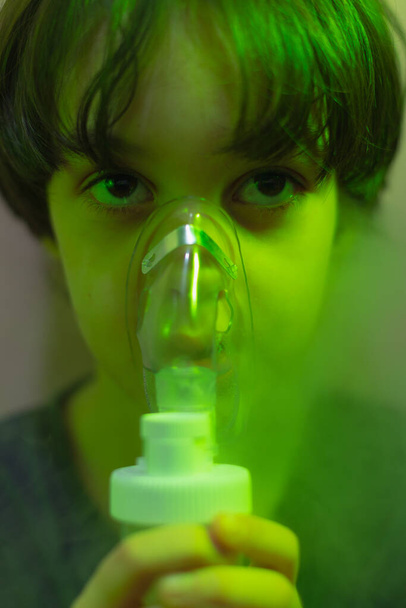 ребенок делает вдох, мальчик вдыхает лекарство через маску, маску туманности, лечение болезни - Фото, изображение