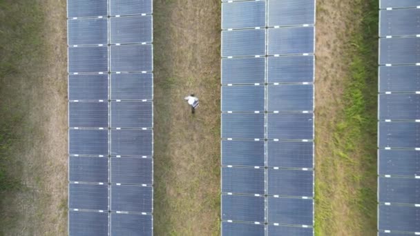 技術者の女性は太陽電池パネルの建設を検査します。産業グリーン電力の再生可能エネルギー。ソーラーファームでの太陽電池パネルのトップの空中ビュー。産業再生可能エネルギー. - 映像、動画