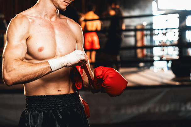 Határozott kaukázusi férfi bokszoló izomzattal fizikai felkészültség test burkolja a kezét és a dons vagy visel boksz kesztyű, felkészülés intenzív boksz edzés a ringben az edzőteremben. Impetusz - Fotó, kép